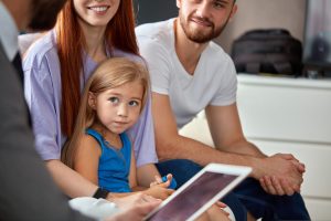 Close-up of a smiling young girl with her parents outdoors.